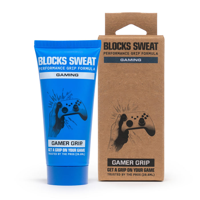 Blue Gamer Grip for Gaming 1 oz tube next to its kraft retail box, both reading Blocks Sweat Performance Grip Formula, on a gaming desk