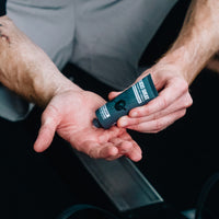 Lifter squeezing Gamer Grip for Strength & Fitness from the charcoal tube into an open palm